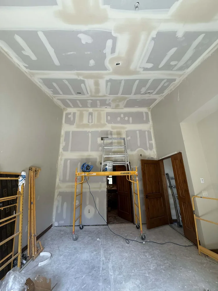 Drywall finishing on a two-storey wall from rolling scaffold