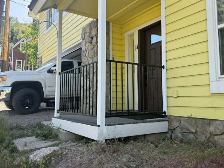 New black metal porch railing installed on a covered front porch
