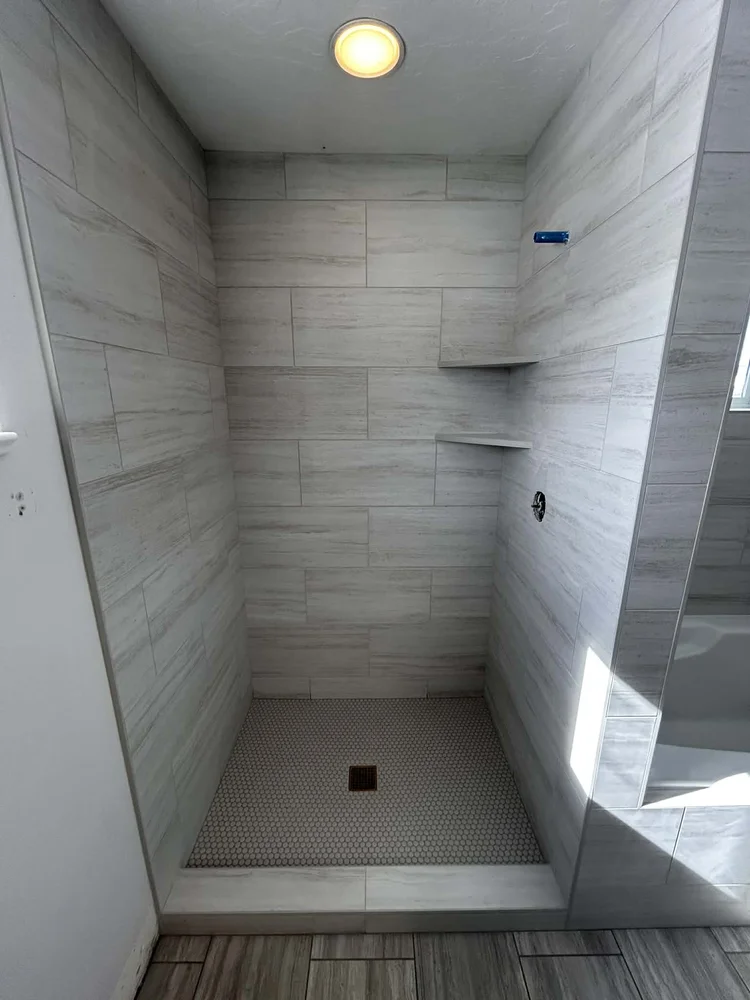 Finished walk-in shower with large-format tile and penny-round floor